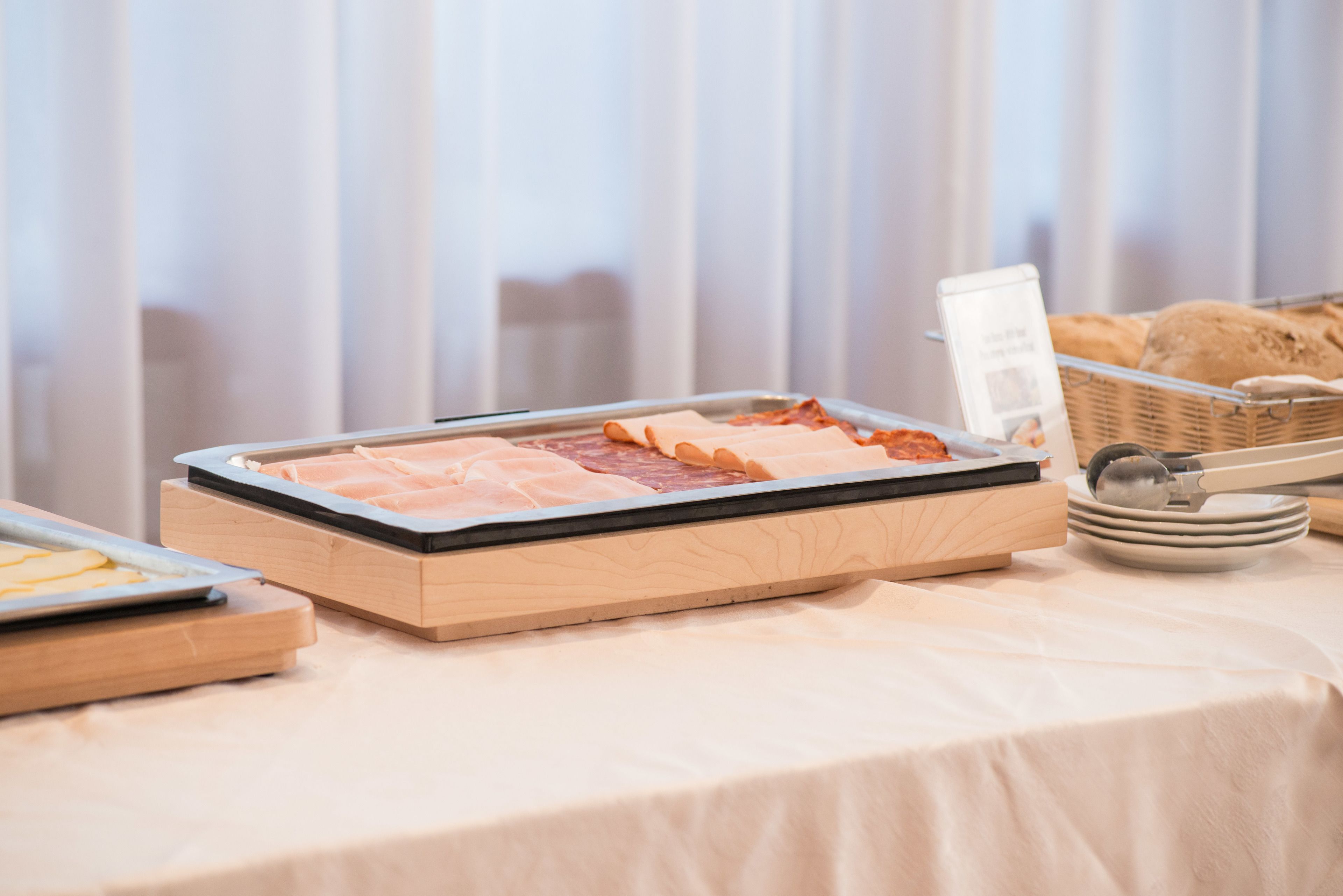 Una mesa de buffet con diferentes alimentos, incluyendo carnes y una cesta de pan.
