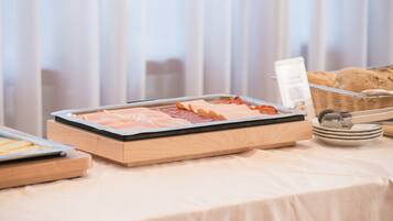 Una mesa de buffet con diferentes alimentos, incluyendo carnes y una cesta de pan.
