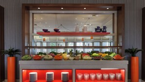Una barra de buffet con diversos alimentos y platos apilados.