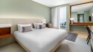Una habitación de hotel con una cama grande, un escritorio, una silla y un balcón con vistas.