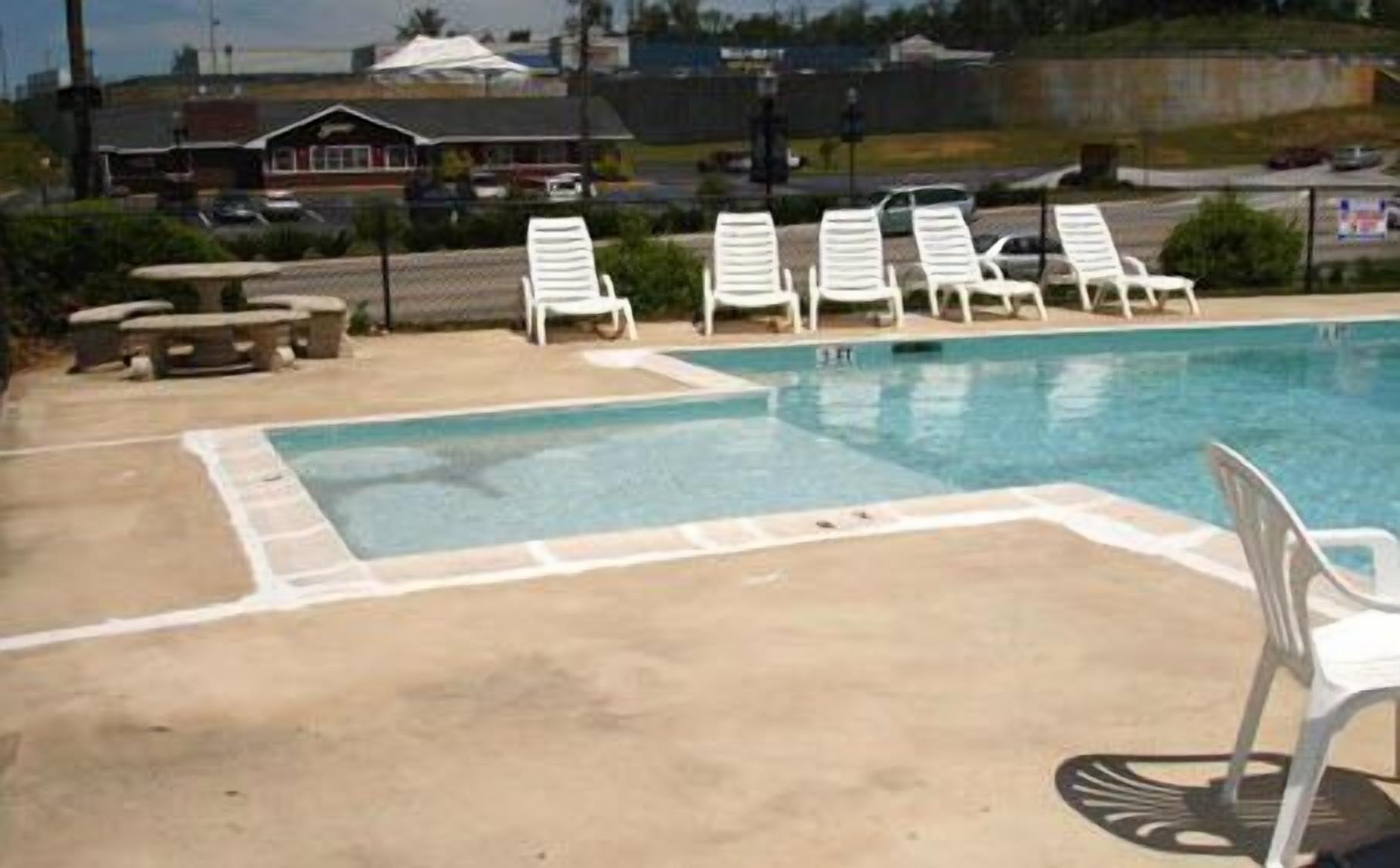 A swimming pool with white lounge chairs and a picnic table.