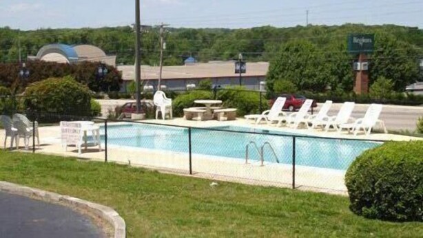 A swimming pool with lounge chairs and a sign indicating a restaurant. - Scottish Inns (Commerce)