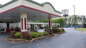 A gas station with a low clearance sign, a blue truck, and a gas pump. - Scottish Inns (Commerce)