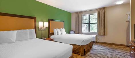 A hotel room with two beds, a large window with curtains, a desk with a lamp, and a television.