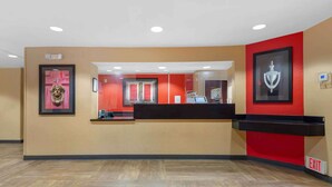 A reception area with a counter, framed artwork, and an exit sign. - Extended Stay America Suites Atlanta Perimeter Crestline (Atlanta)