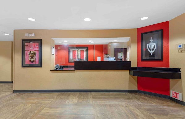 A reception area with a counter, framed artwork, and an exit sign.