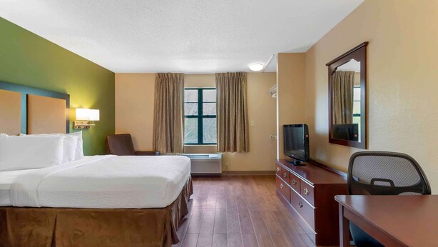 A hotel room with a bed, a desk, a chair, a television, and a window with curtains. - Extended Stay America Suites Atlanta Perimeter Crestline (Atlanta)