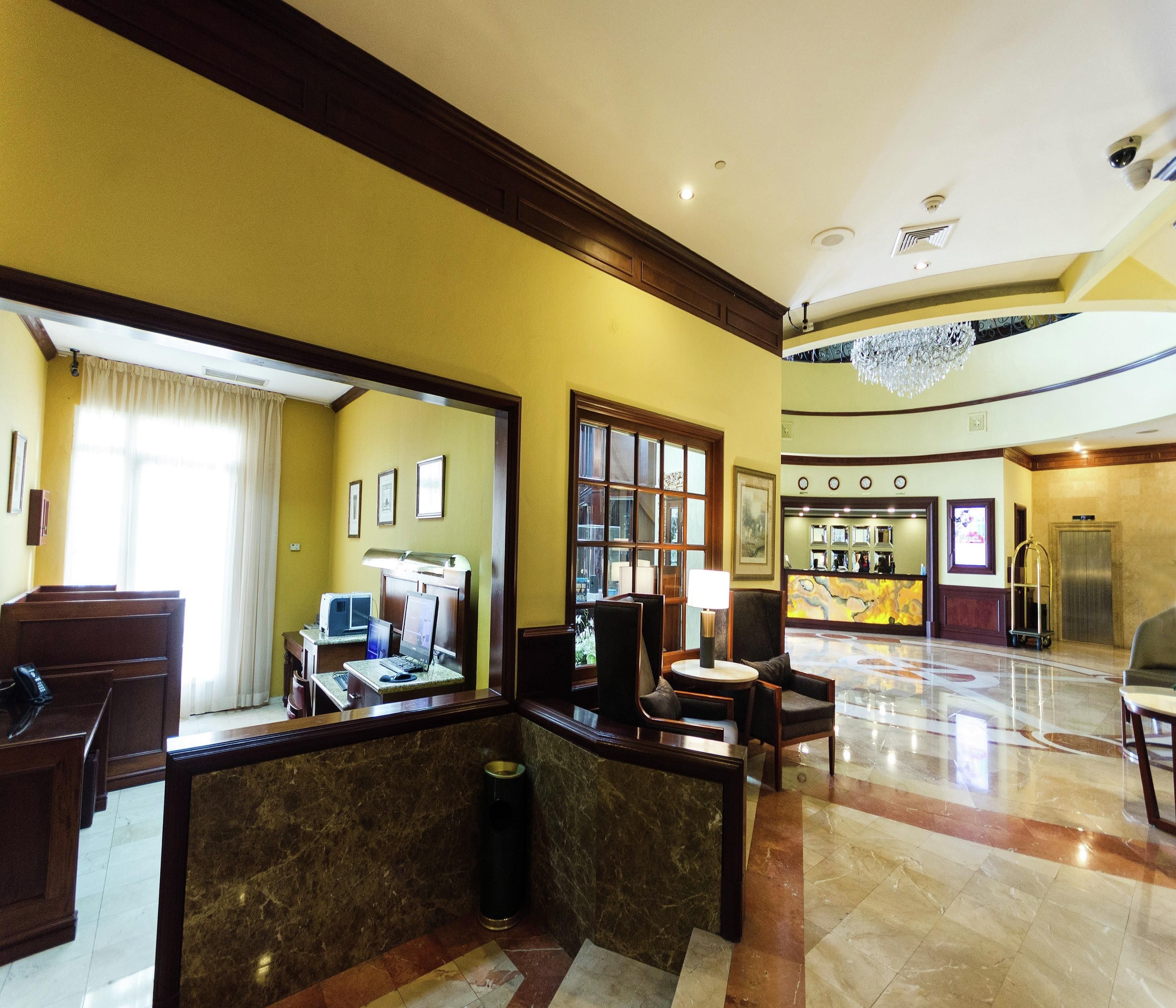 A hotel lobby with a reception desk, seating area, and a reception counter.