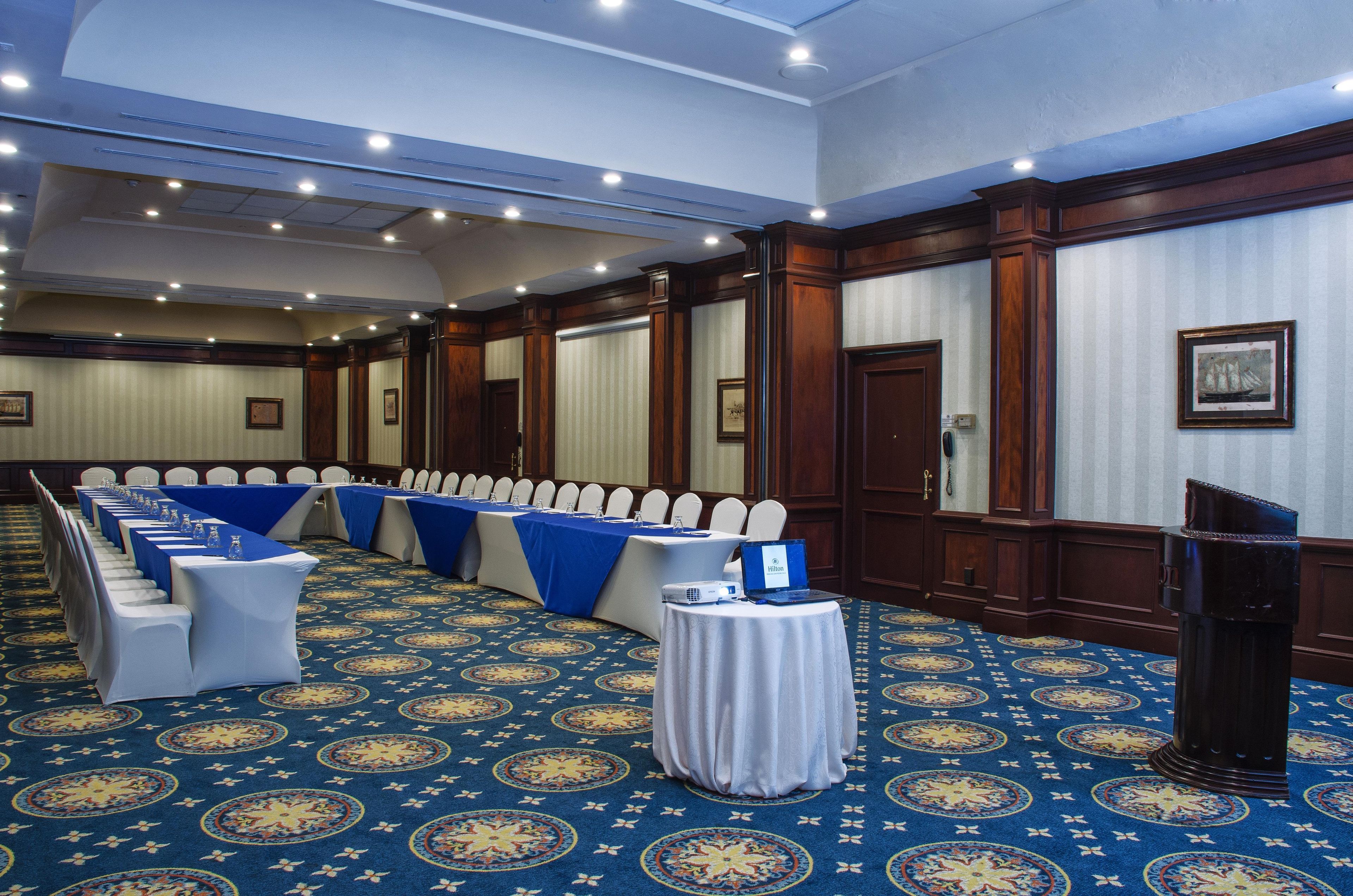 Una sala conferenze con file di tavoli, sedie e un podio.