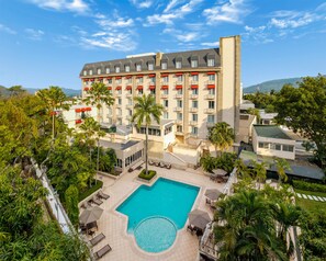 A hotel with a pool, outdoor seating, and a view of the surrounding landscape.