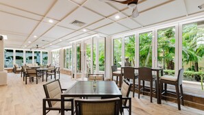 A spacious dining area with a high ceiling, large windows, and a view of greenery outside. - Hilton Princess San Pedro Sula (San Pedro Sula)