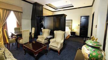 Habitación de hotel con una cama grande, dos sillones, una mesita, un florero decorativo y un armario.