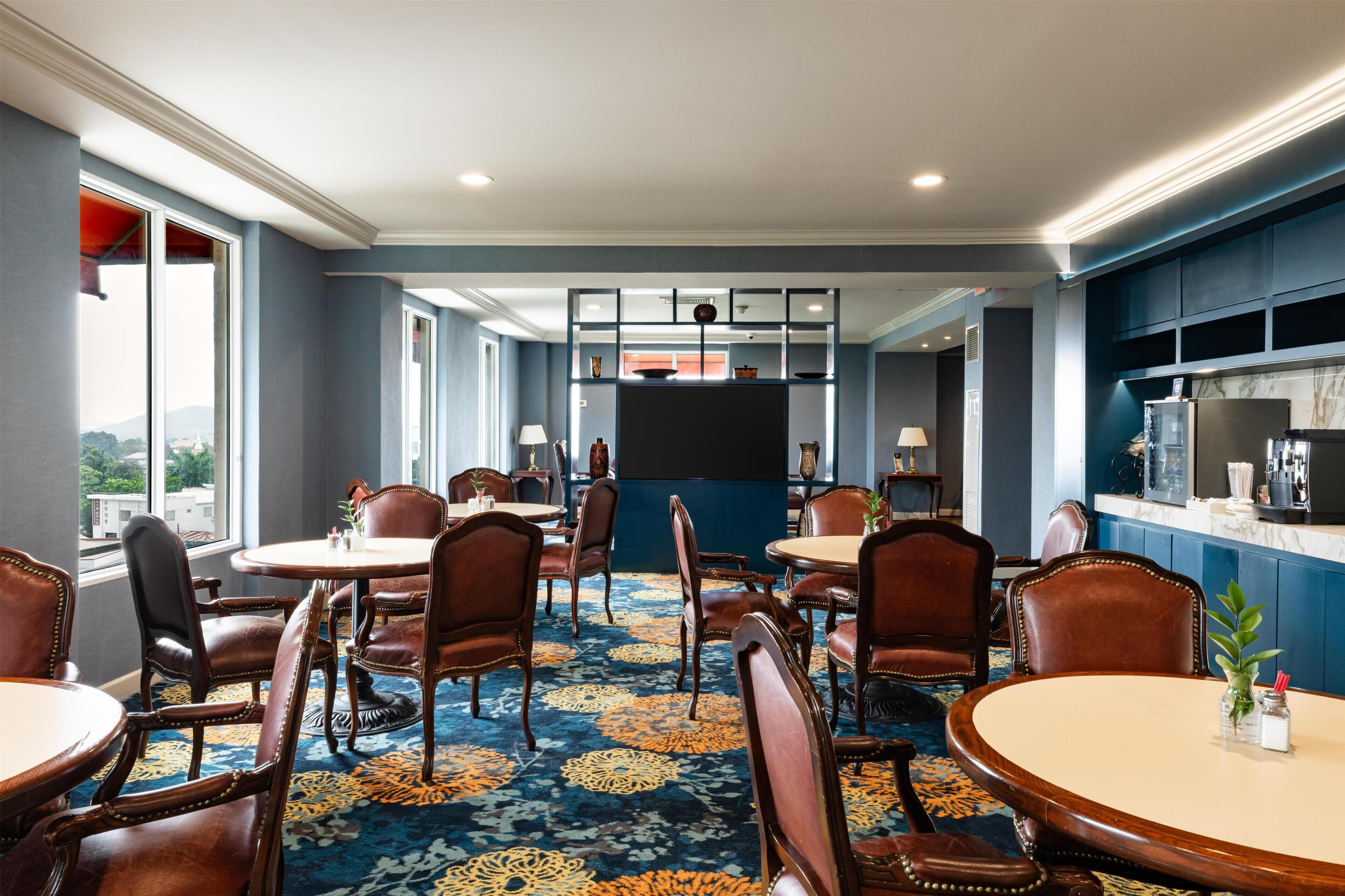 Une chambre d’hôtel dotée d’une grande fenêtre, d’un téléviseur à écran plat, d’un minibar et d’un sol recouvert de moquette.