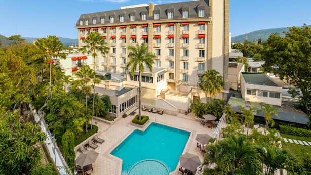 A hotel with a pool, outdoor seating, and a view of the surrounding landscape. - Hilton Princess San Pedro Sula (San Pedro Sula)