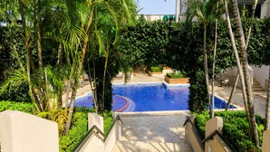 A pool area with steps leading down to it, surrounded by palm trees and greenery. - Hilton Princess San Pedro Sula (San Pedro Sula)