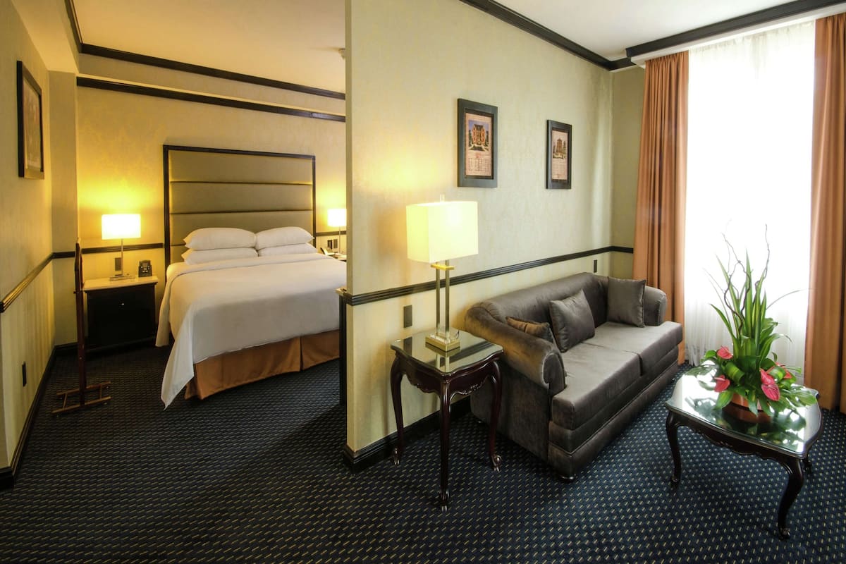Ein Hotelzimmer mit einem Bett, einer Couch, einem kleinen Tisch und einer Lampe.