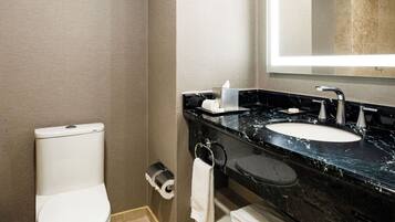 A hotel bathroom with a toilet, a sink with a mirror, and a towel rack.