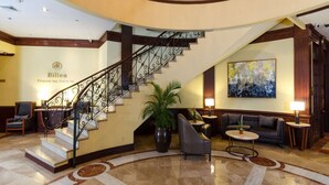 A grand lobby with a marble floor, a curved staircase, and a seating area with sofas and a coffee table. - Hilton Princess San Pedro Sula (San Pedro Sula)