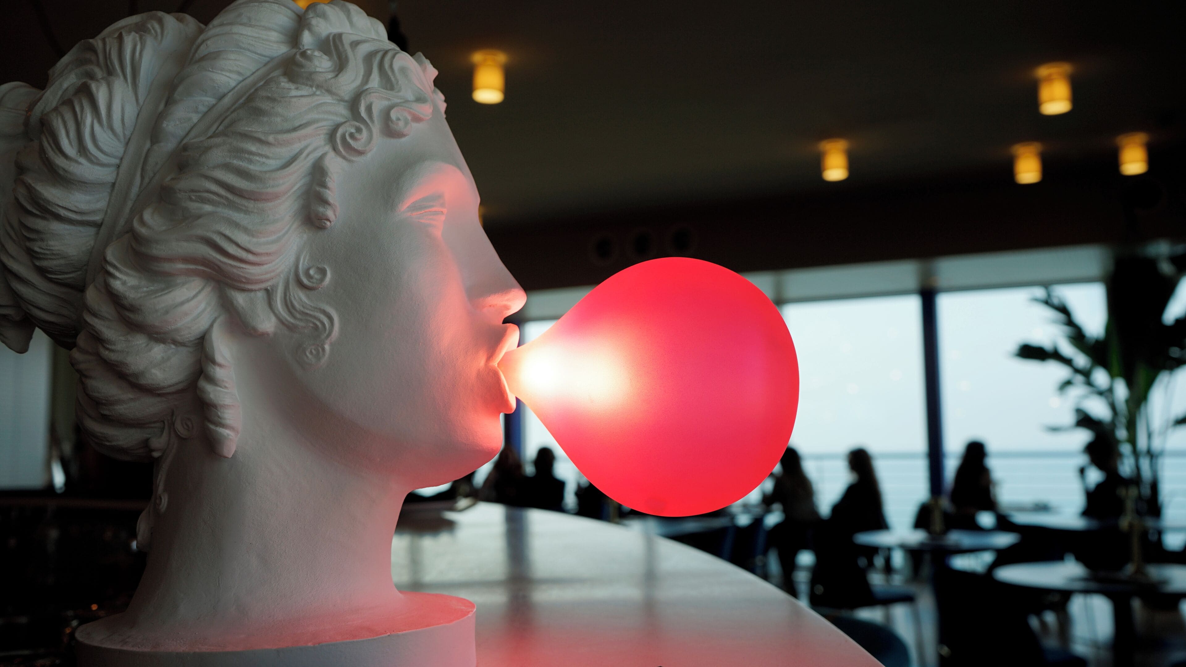 Une sculpture en buste avec un ballon rouge.