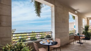 Un balcón con mesa y sillas, con vista a una masa de agua y vegetación.