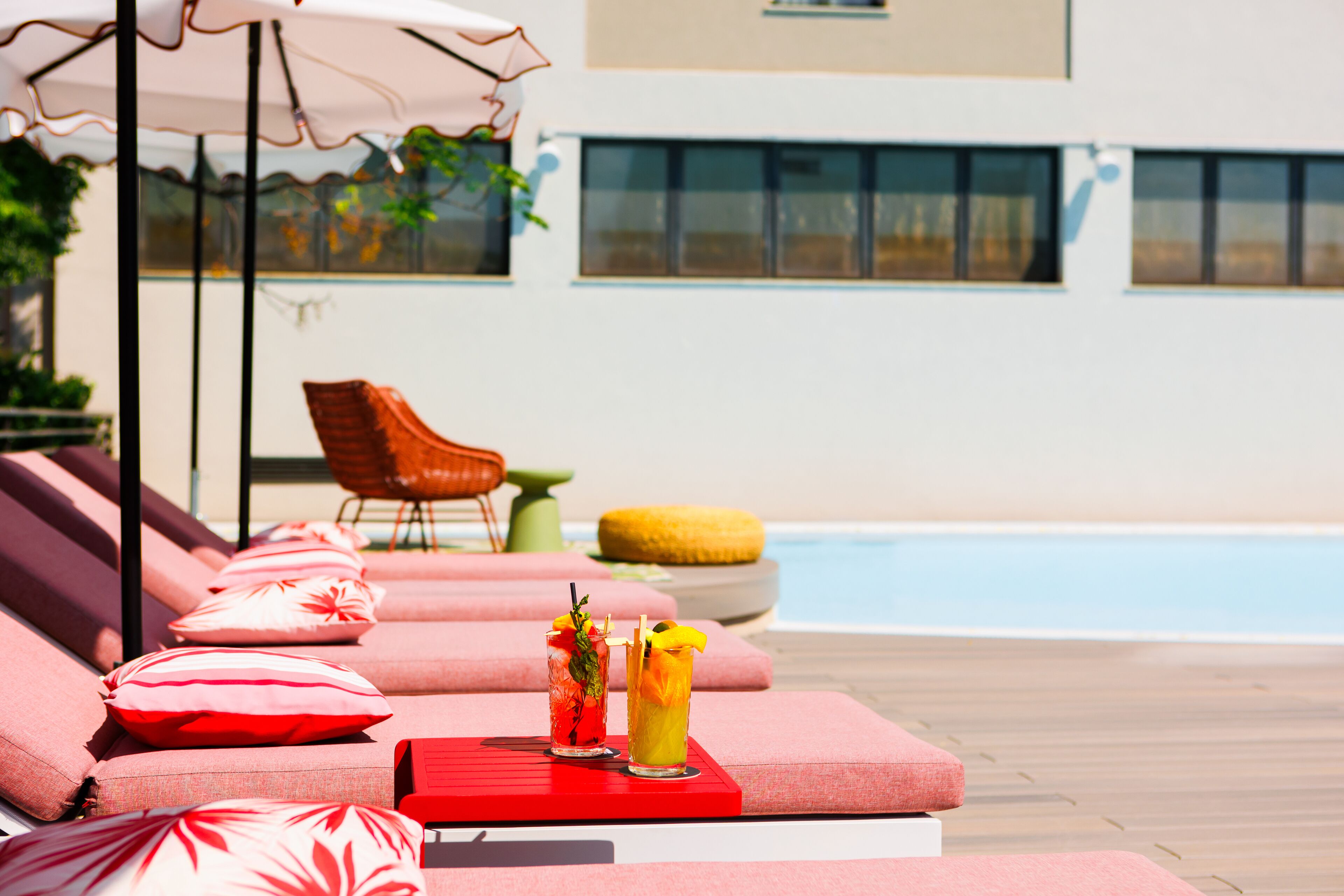 Zona junto a la piscina con sillones de descanso y una mesa con bebidas.