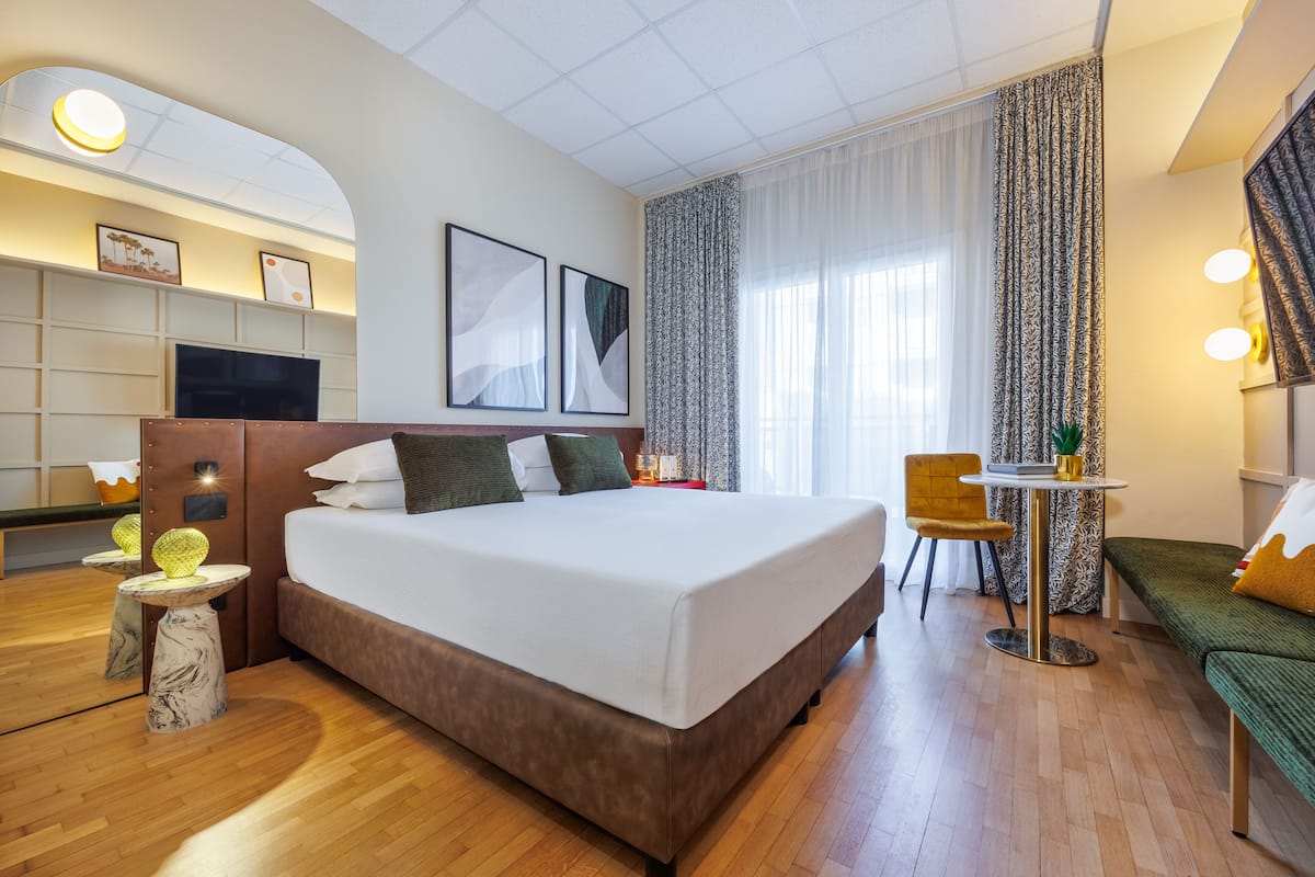 Una habitación de hotel con una cama grande, un escritorio, una silla, una mesita y un sofá.