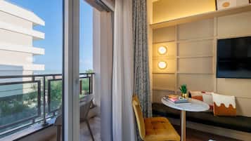 Una habitación de hotel moderna con balcón, sofá, una mesita y televisor.