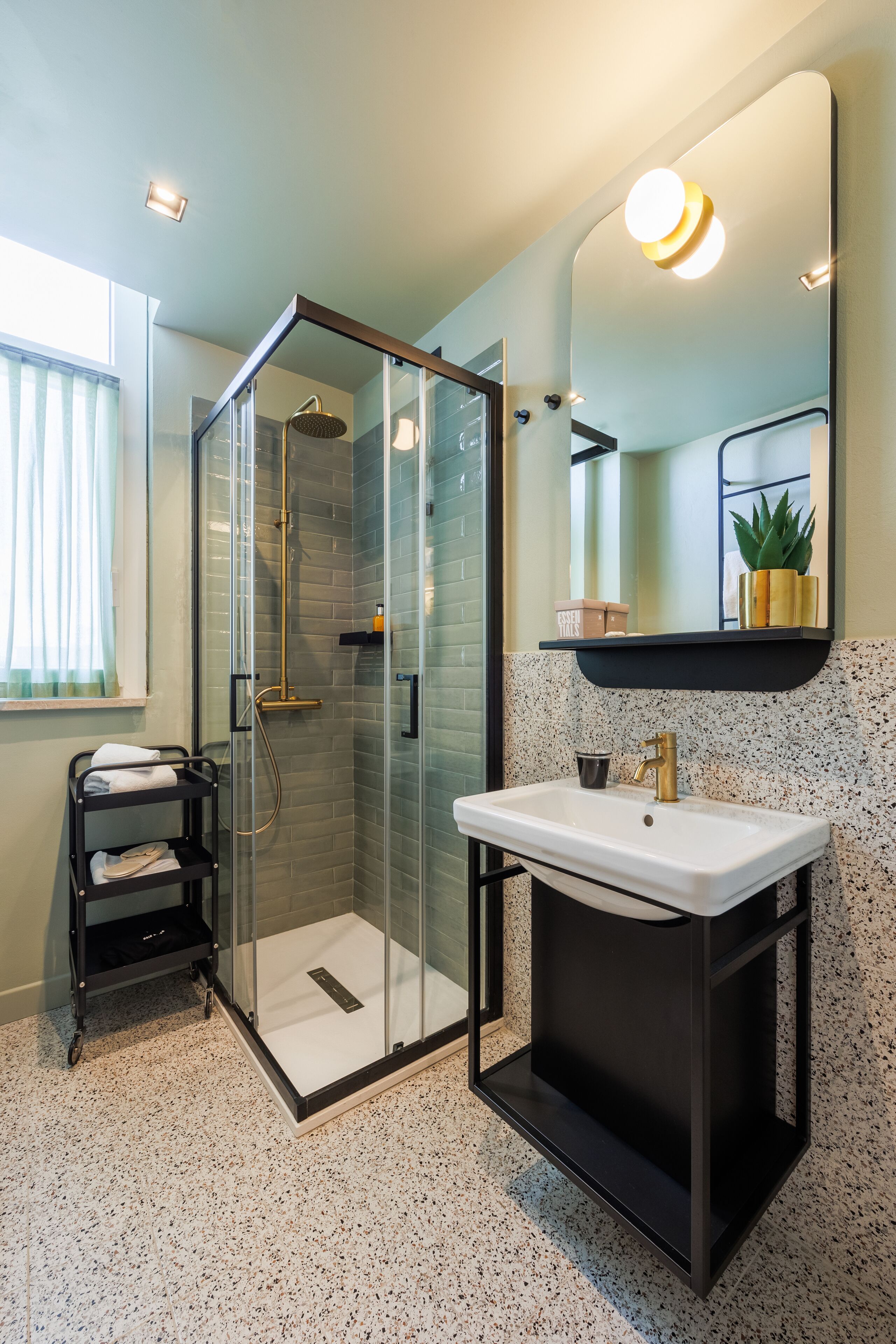 Un baño moderno con ducha de vidrio, lavabo blanco y tocador negro.