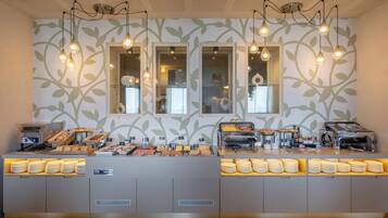 Un comptoir de buffet proposant divers plats et un espace dédié au café, le tout installé devant un mur orné d’un motif de feuilles.