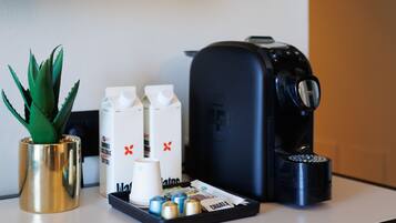 Une machine à café, une petite plante et des briques de lait sur un comptoir.