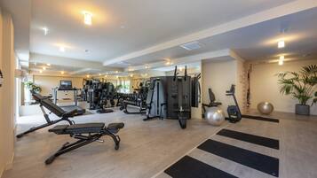 Un gimnasio moderno con diversos equipos de ejercicio, como cintas de correr, máquinas de pesas y pesas libres.