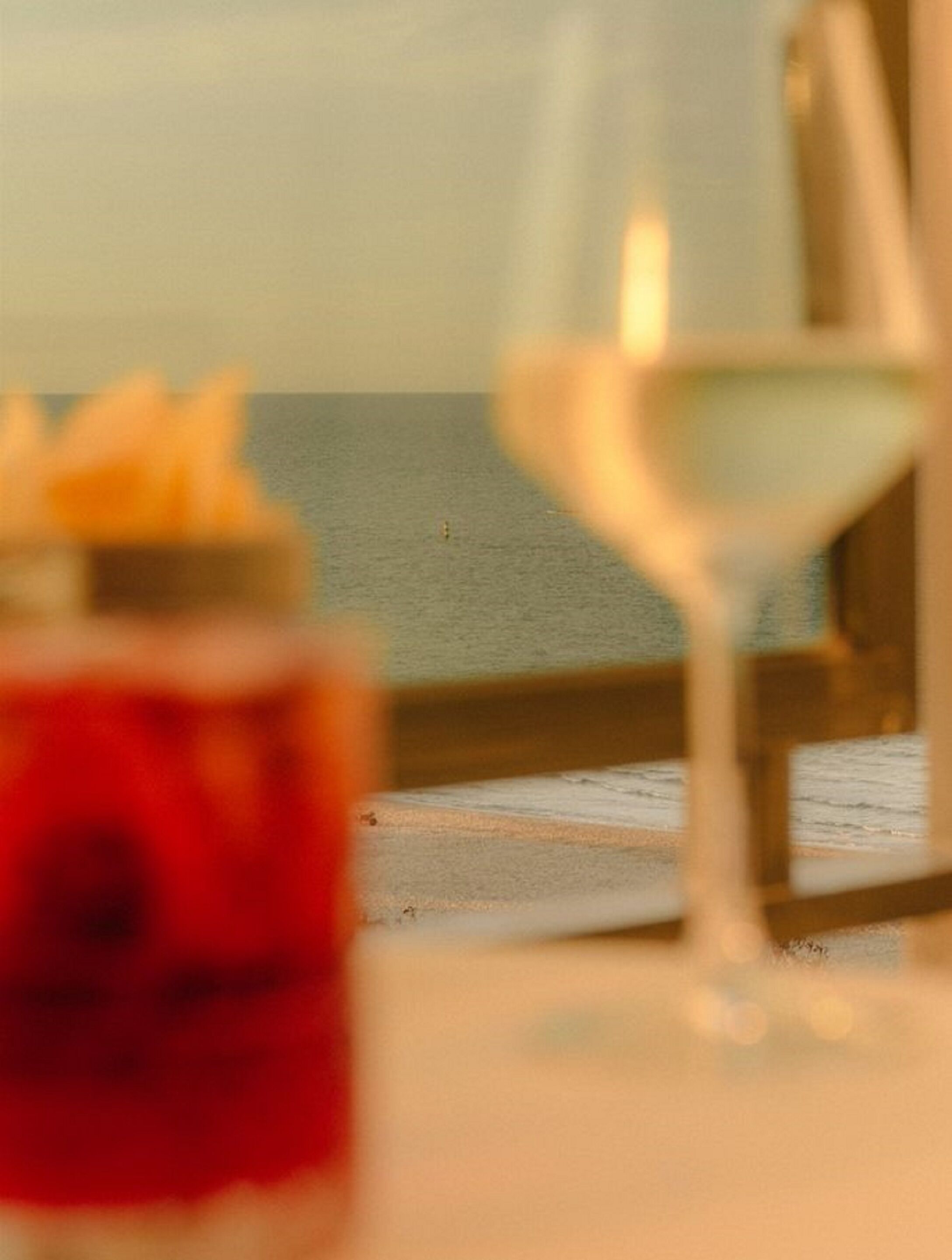 Una mesa con una copa de vino blanco y un postre.