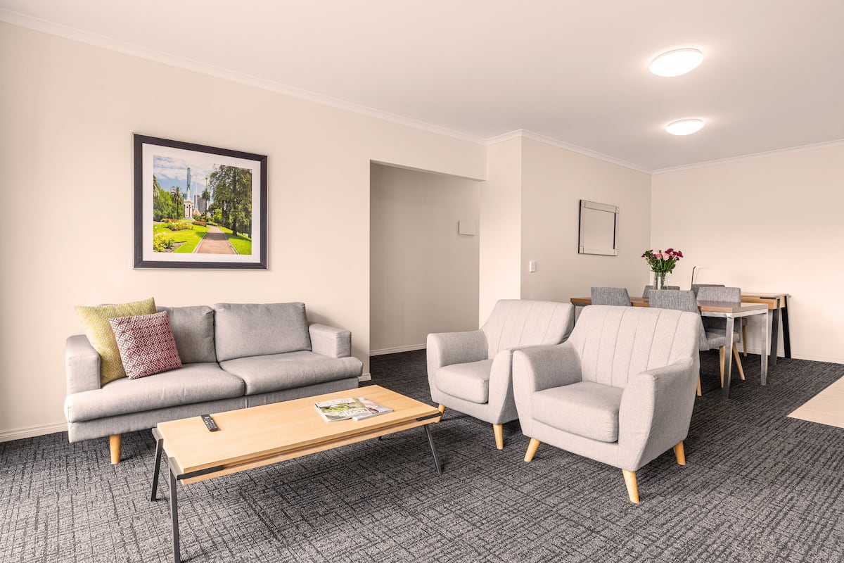 Una sala moderna con un sofá, sillones, una mesa de centro y un comedor con sillas y una mesa.