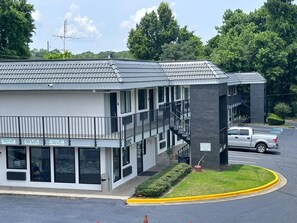 A multi-story hotel with a modern design, featuring balconies, large windows, and a parking area with a white pickup truck. - Masters Inn Atlanta - Doraville at I-85 & 285 (Doraville)