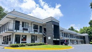 A multi-story hotel with a modern design, featuring balconies and a parking area. - Masters Inn Atlanta - Doraville at I-85 & 285 (Doraville)