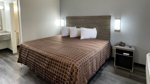 A hotel room with a large bed, a nightstand, a mirror, and a bathroom visible through an open door. - Masters Inn Atlanta - Doraville at I-85 & 285 (Doraville)