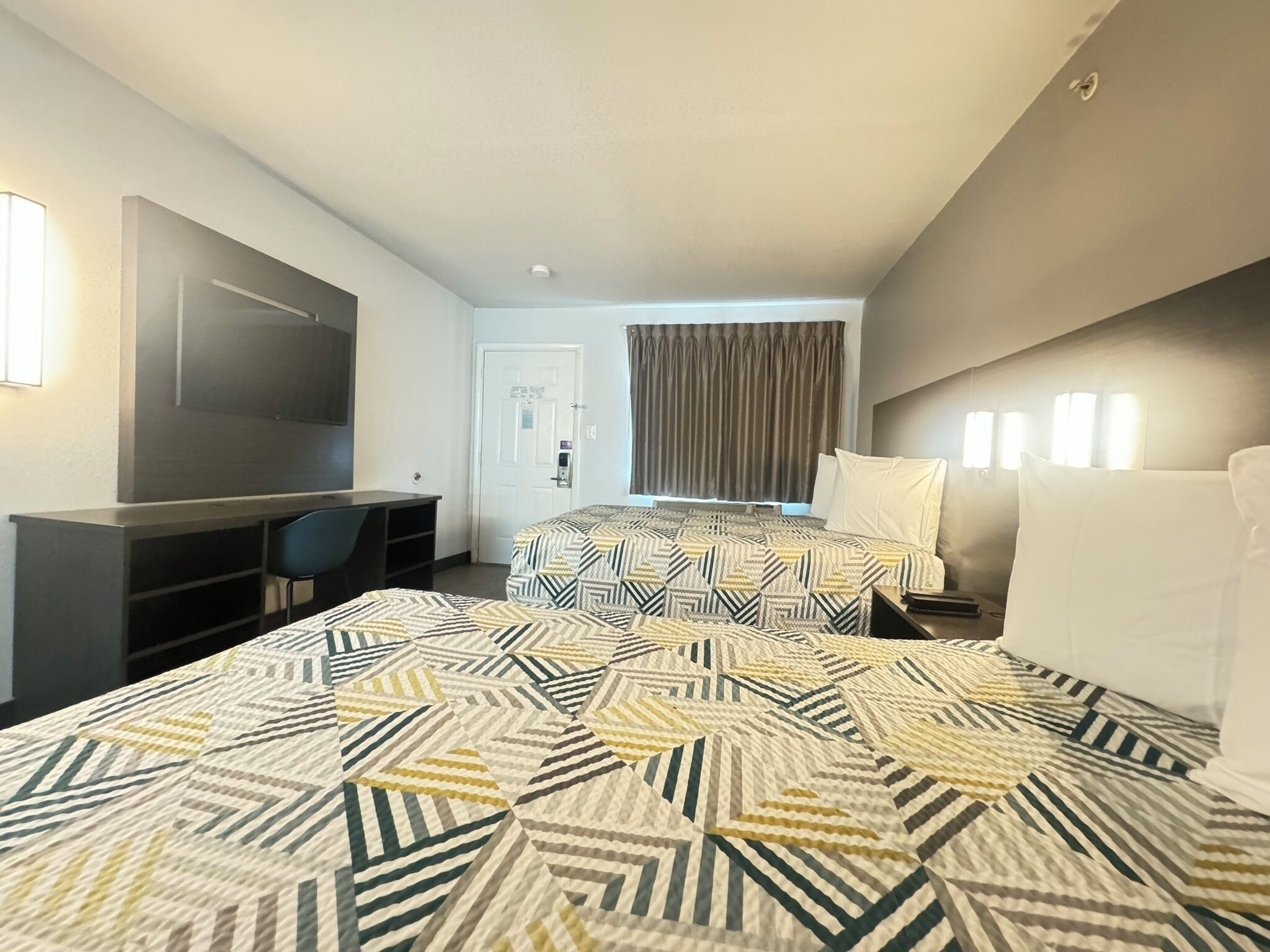 Une chambre d’hôtel avec un grand lit, un bureau, une chaise, une télévision et une porte.