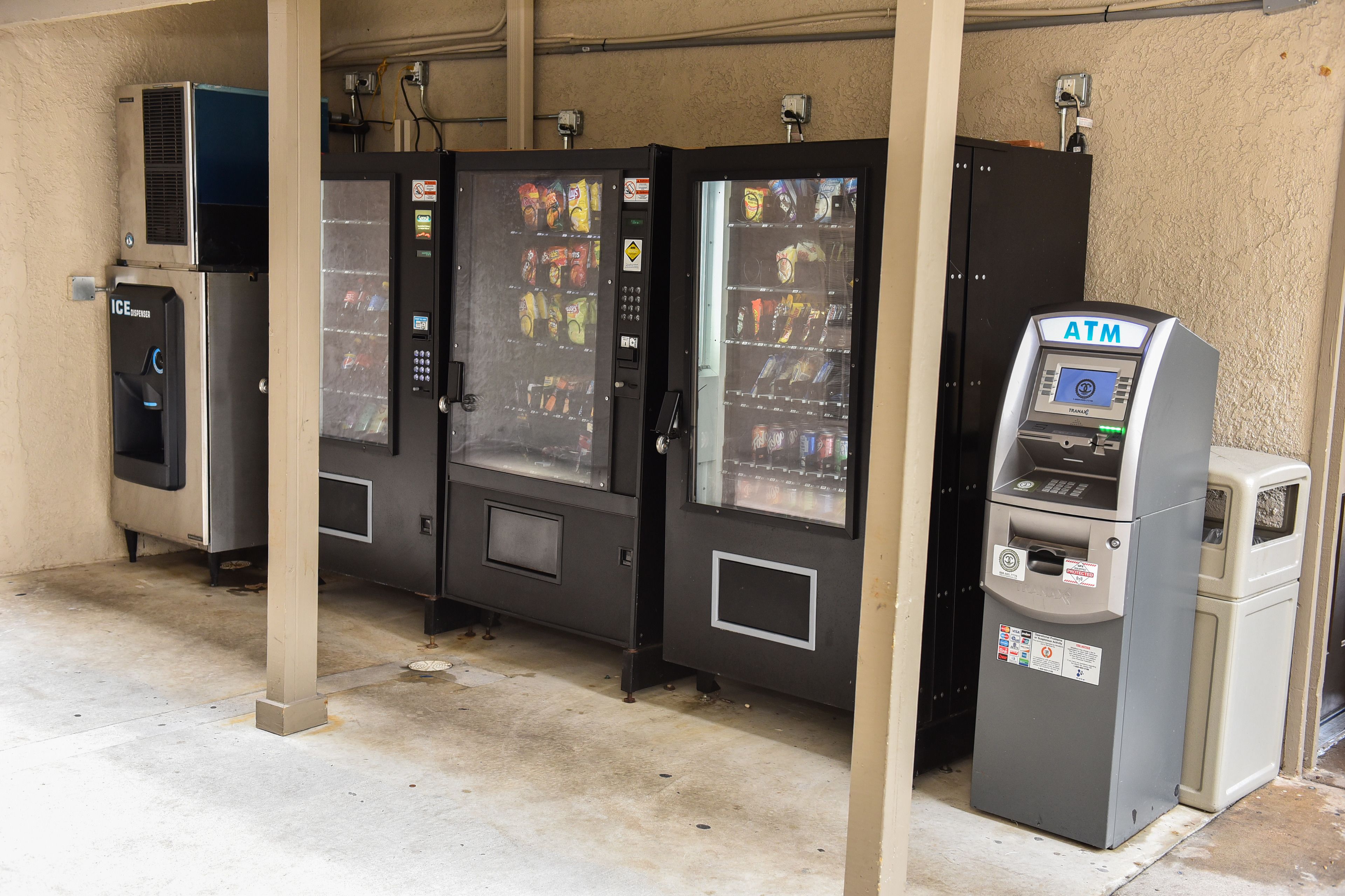 A row of vending machines and an ATM in a commercial setting.