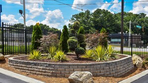 A landscaped garden with a brick border, various shrubs, and a large rock centerpiece. - Masters Inn Tucker (Decatur)