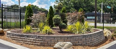 A landscaped garden with a brick border, various shrubs, and a large rock centerpiece.