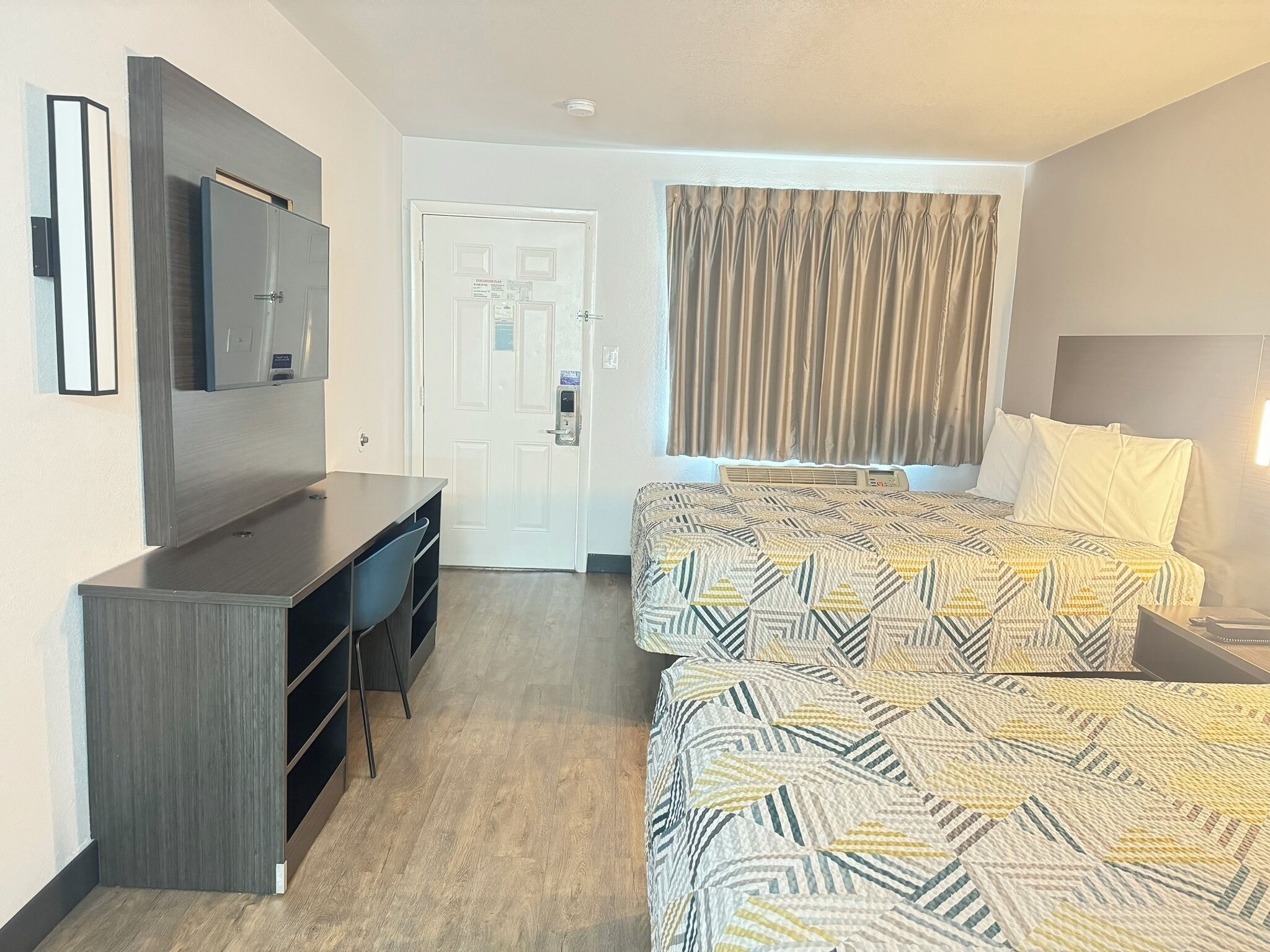 Une chambre d’hôtel avec un lit, un bureau, une télévision et une porte.