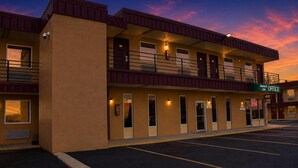 Ein Motel mit zweistöckiger Bauweise, mehreren Zimmern und einem Parkplatz.