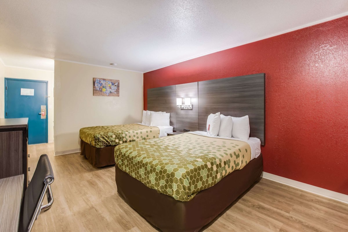 Une chambre d’hôtel avec deux lits, un bureau et une chaise.