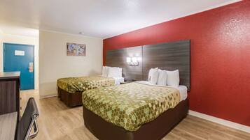 A hotel room with two beds, a desk, and a chair.