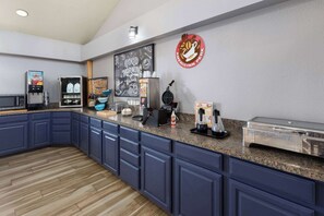 A kitchen area with a coffee station, a chalkboard with drawings, and a sign for Americinn Perk. - AmericInn by Wyndham Oscoda Near AuSable River (Oscoda)