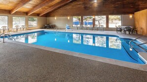 Piscina interna com teto de madeira e janelas amplas.