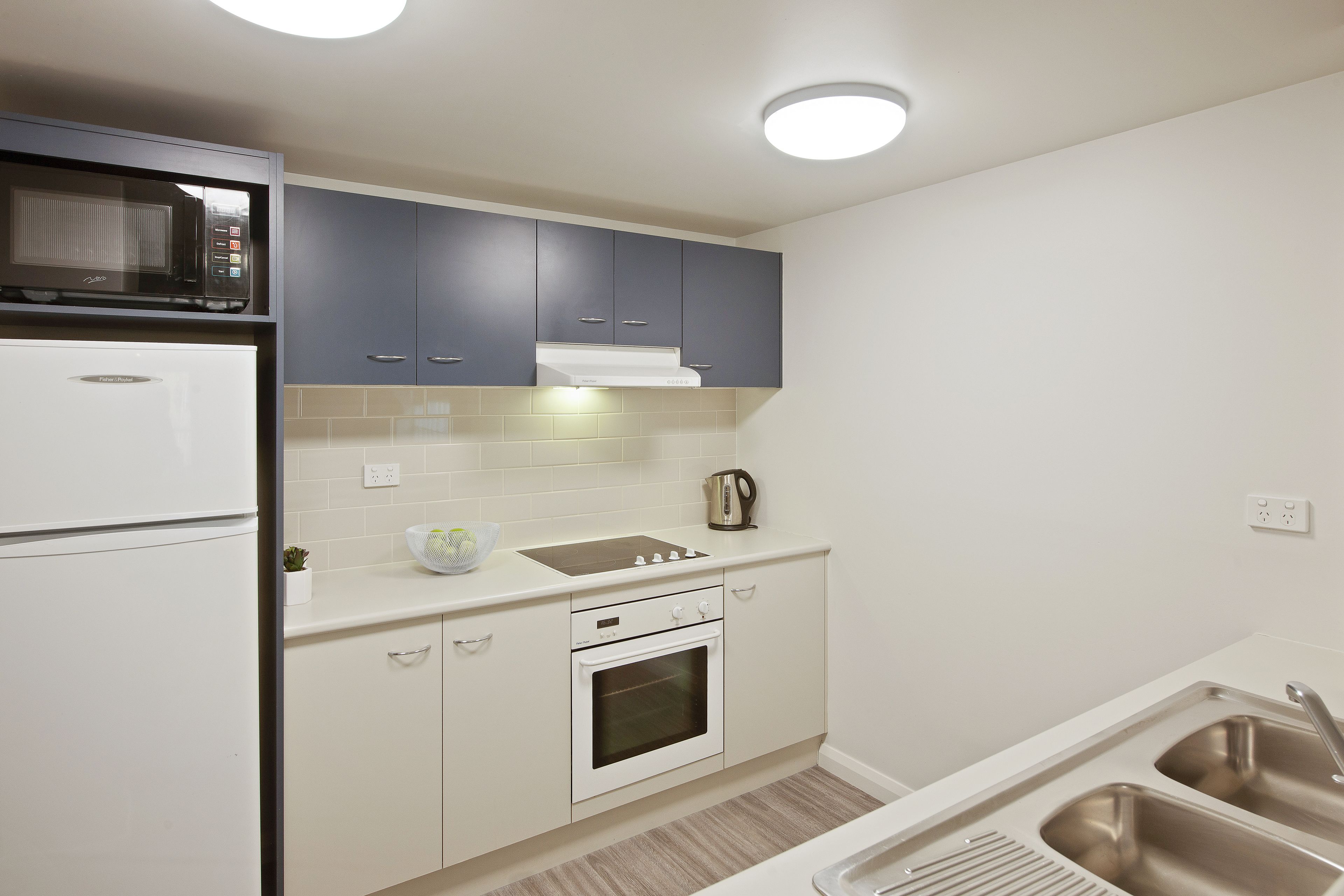 A compact kitchen with a white refrigerator, a microwave, a stove, and a sink.
