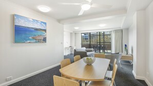 Et moderne mødelokale med et rundt bord, træstole, en loftvifte og et stort vindue med udsigt til det fri.