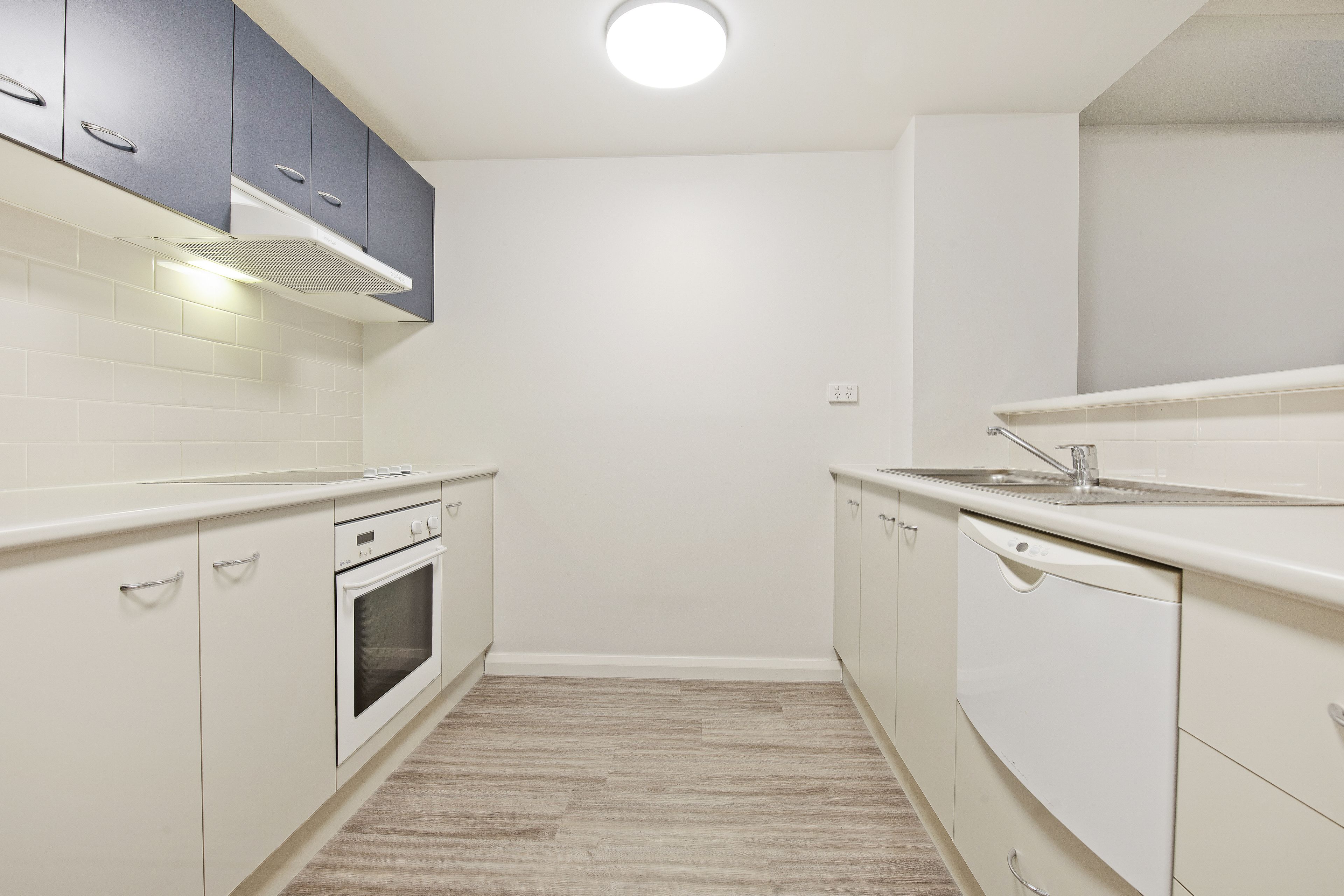 A modern kitchen with white cabinets, a built-in oven, and a dishwasher.