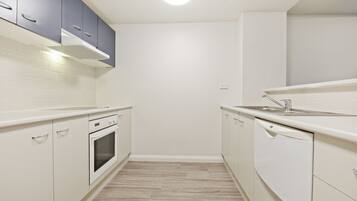 A modern kitchen with white cabinets, a built-in oven, and a dishwasher.